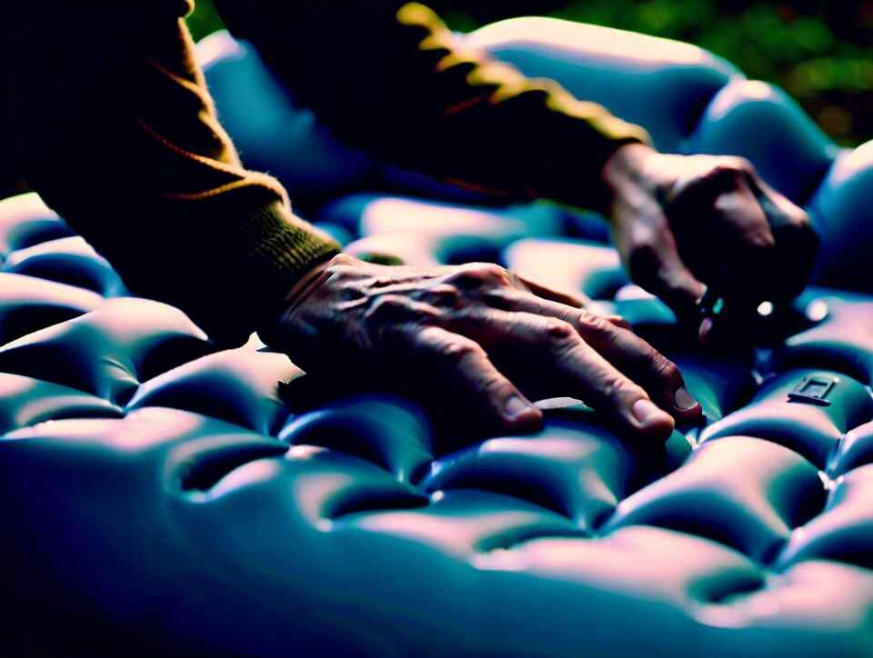 A person carefully patching up a small hole on an inflatable air mattress.